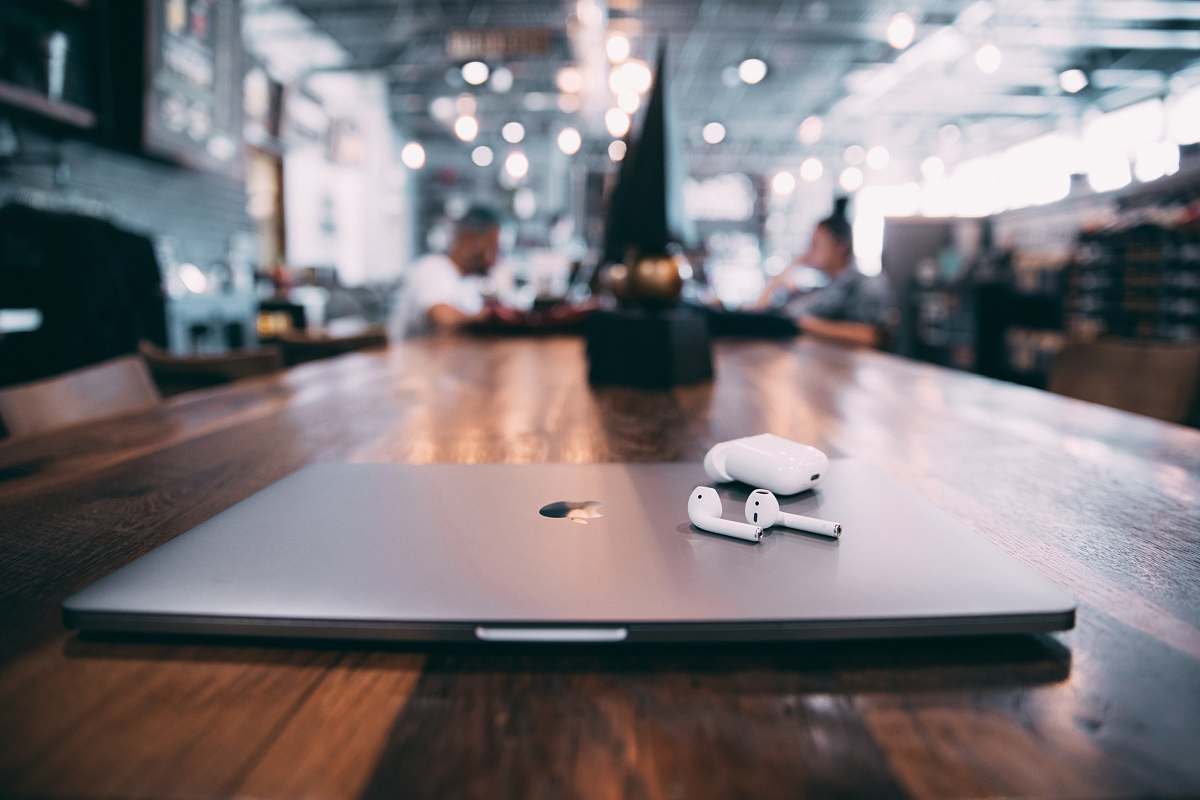 coffee table selective focus photography of white AirPods with charging case on silver MacBook on table furniture